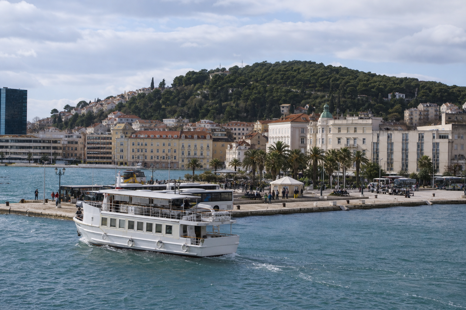 Passenger ferry leaving a Croatian coastal city with buses and waterfront buildings nearby